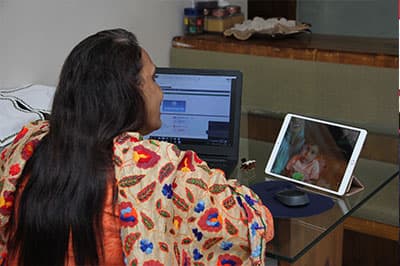 A Shaba clinician at a computer and tablet during a remote session