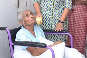 A clinician sits beside an elderly patient in a wheelchair