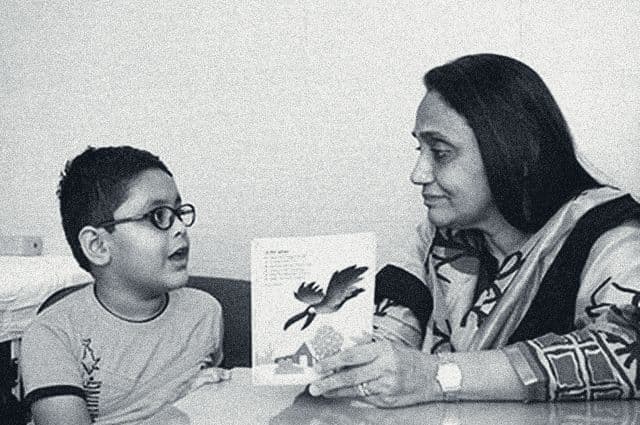 A therapist holds up a picture book for a boy in glasses