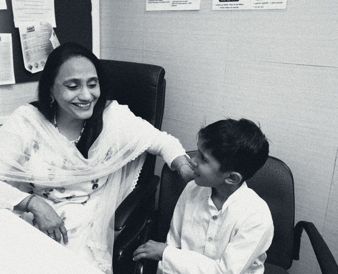A clinician and a young boy smile at each other across the consultation desk at Shaba